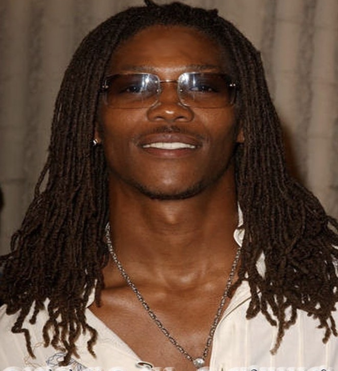Dame Lee wearing glasses and long locs